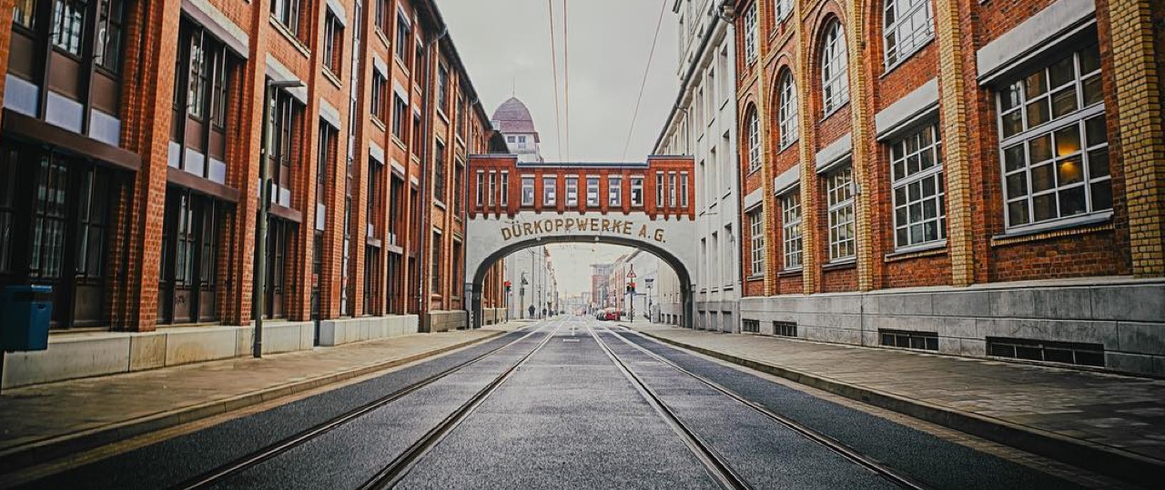 Leere Straße mit roten Backsteingebäuden und Brücke mit Aufschrift Dürkoppwerke