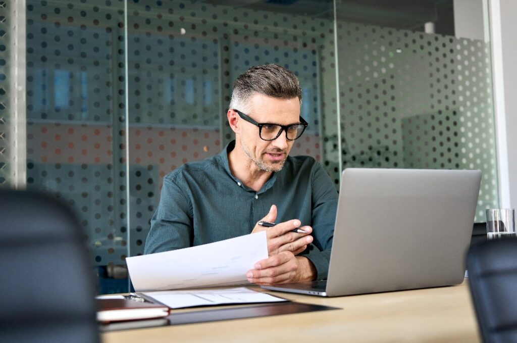 Reifer Geschäftsmann mit Laptop im Gespräch über einen virtuellen Videoanruf.